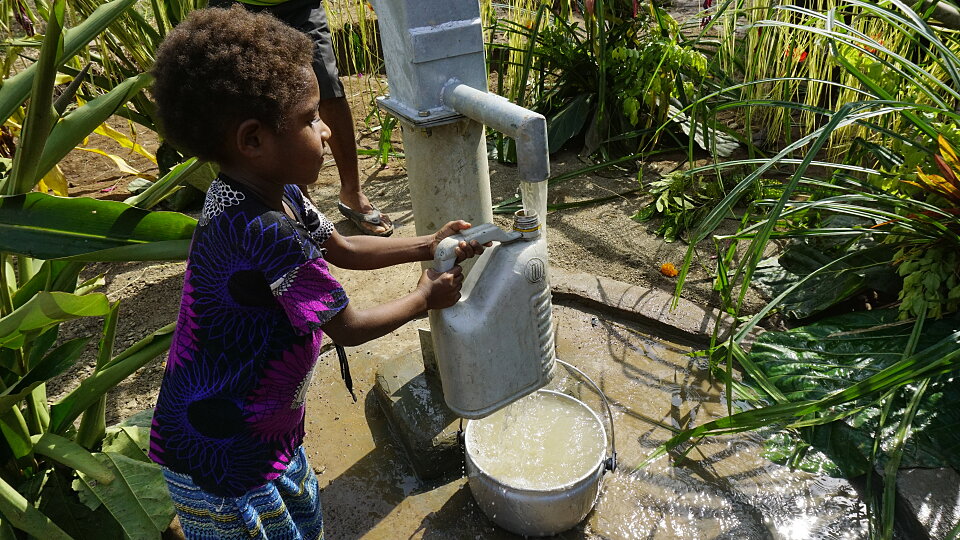 papua new guinea child gets drink of clean water