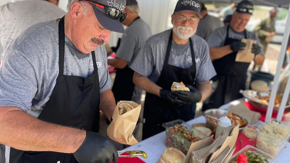 tbm volunteers work in a line to prepare meals after disasters